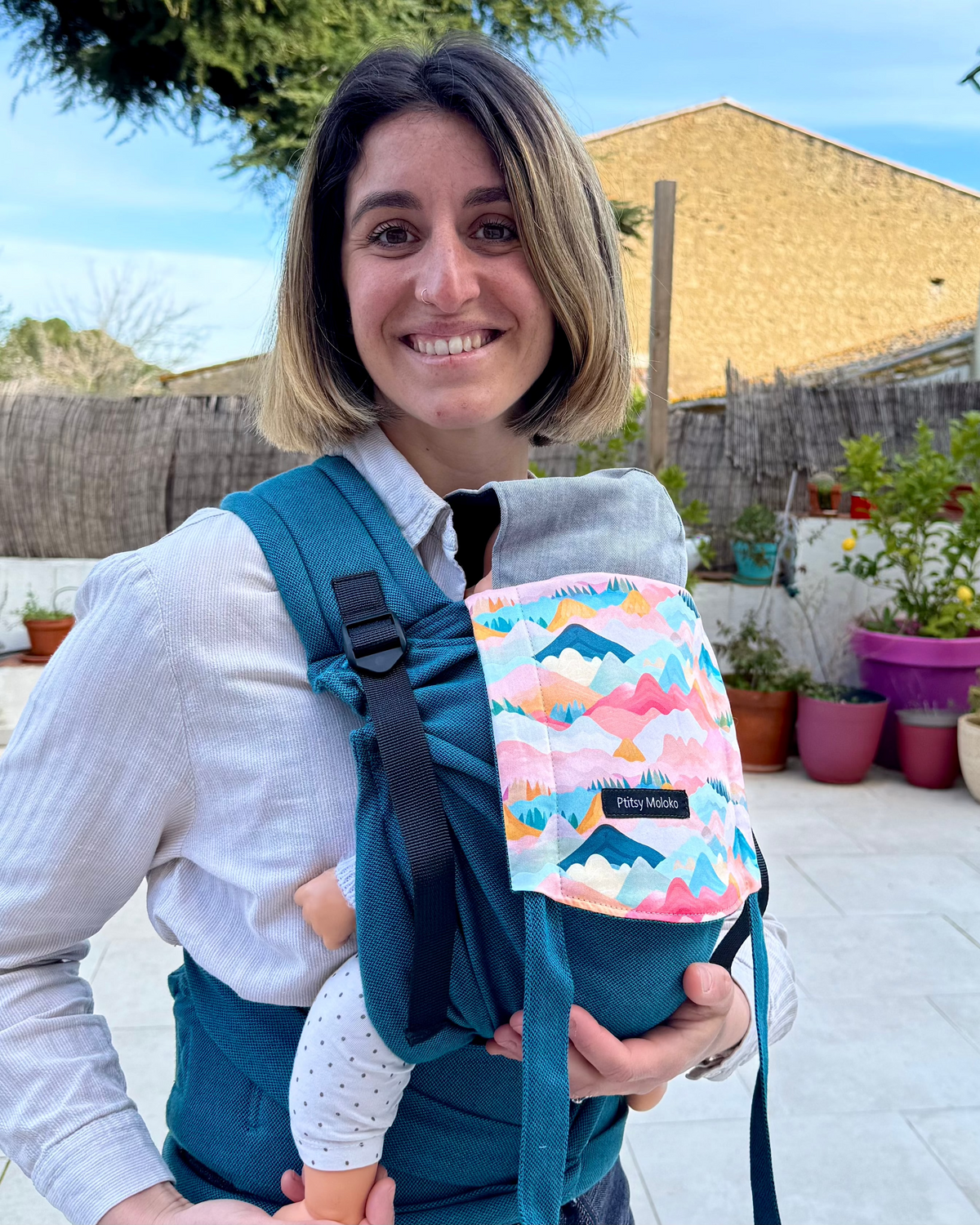 porte-bebe nouveau né en coton bio, ergonomique et confortable pour le porteur. Coloris bleu mediterranée, motifs de montagnes colorées